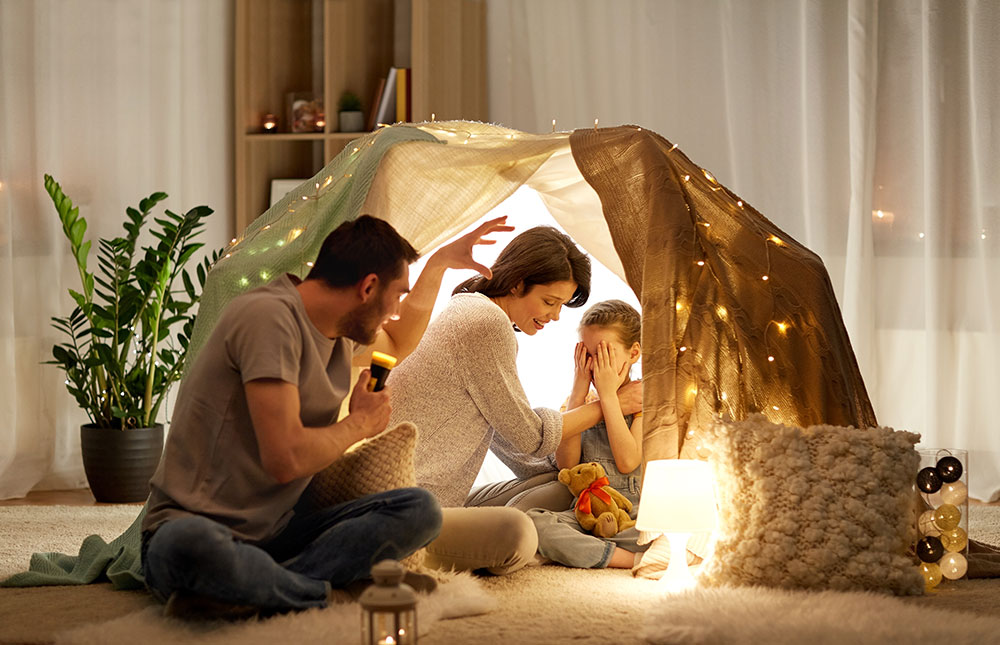 Family in a fort in the family room with beautiful lights, enjoying time together